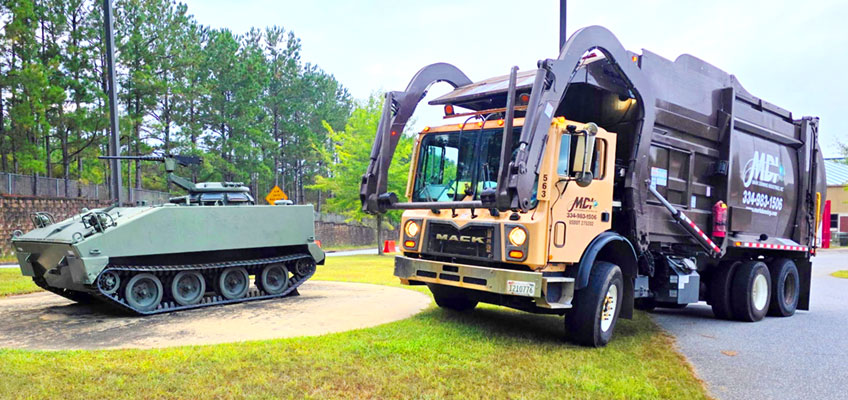 MDI front load garbage truck parked next to an armored personell carrier at Ft Benning, GA.